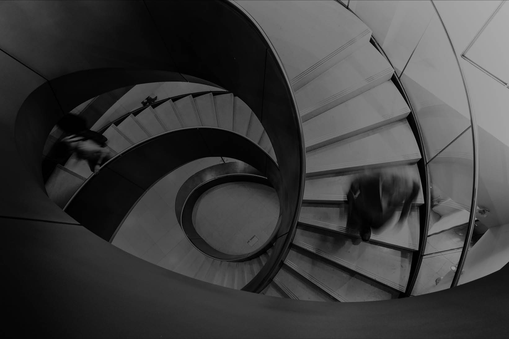 People moving on a curved staircase in a modern building interior - Used on Capco Success Stories