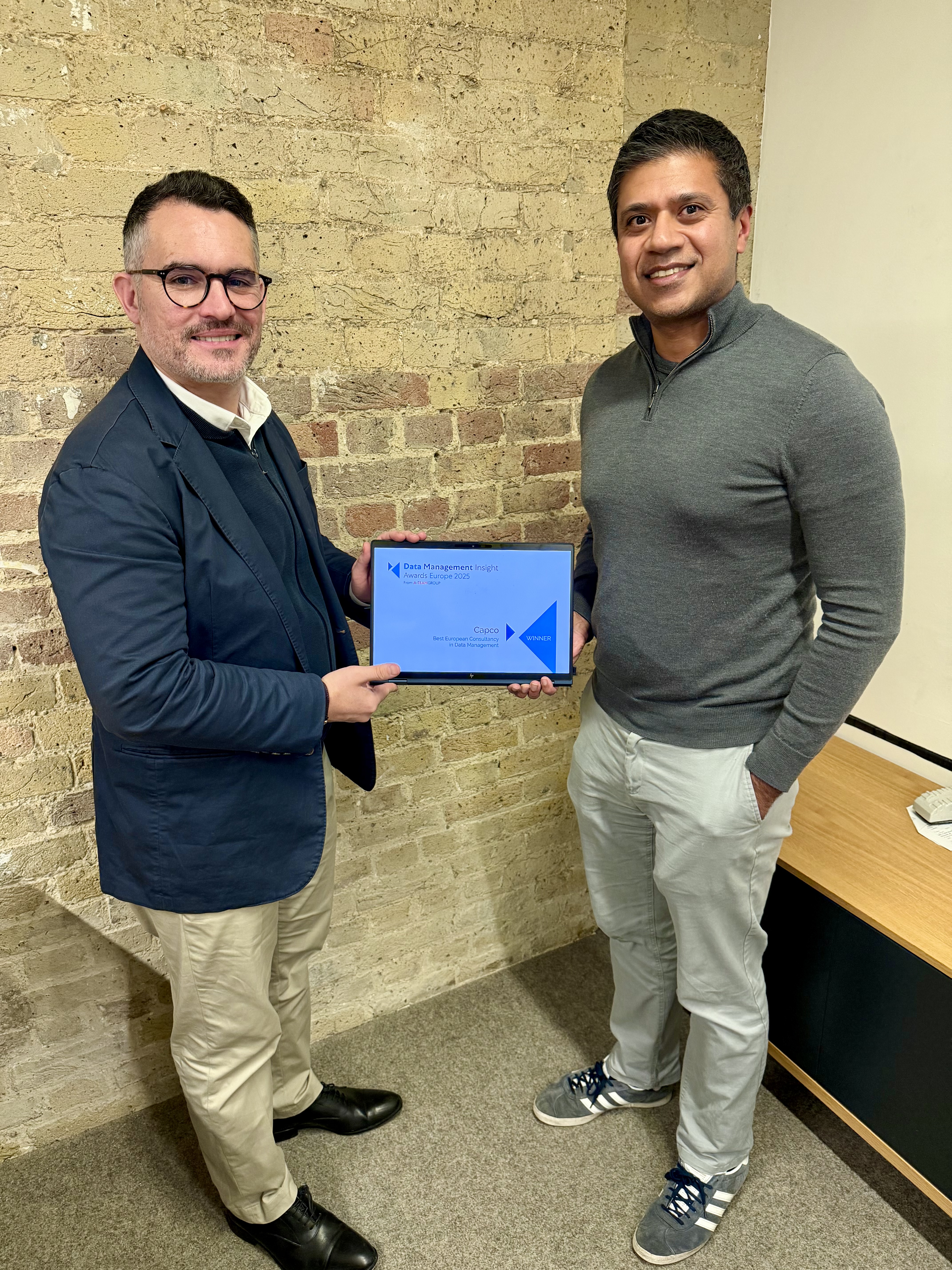 Two Capco Data Partners, Thomas Evans and Rehaan Anjum, standing together holding a winners’ certificate for the Data Management Insight Awards Europe 2025.