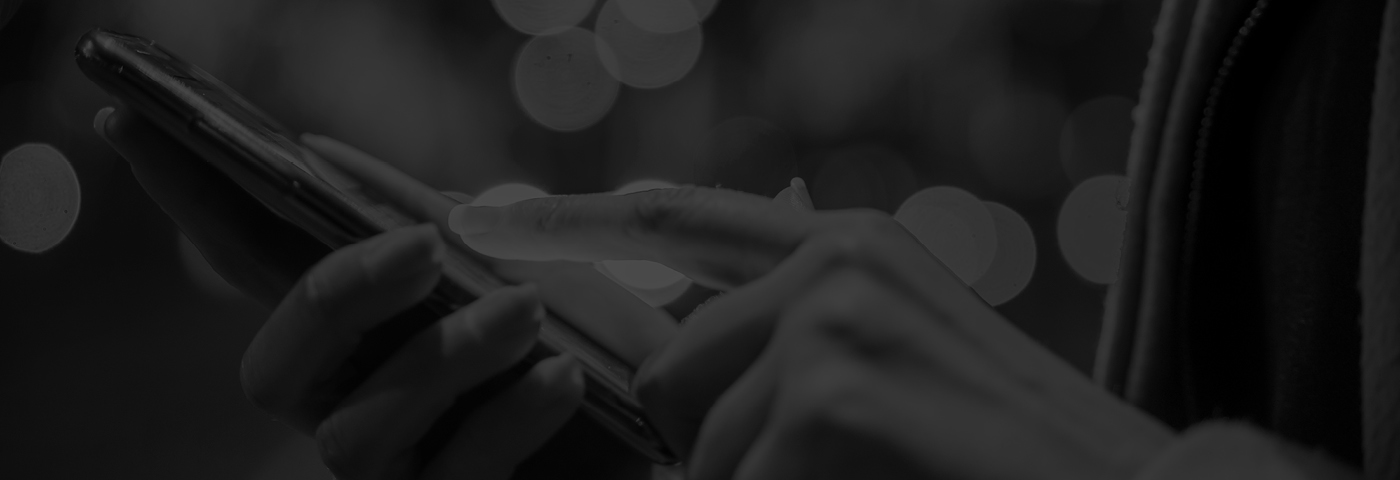 Close-up of a person using a smartphone against a blurred city-light background.