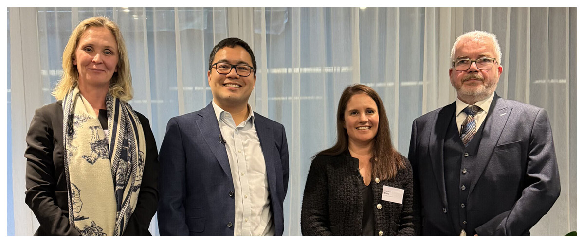 Four attendees posing at a Capco corporate event with conference backdrop