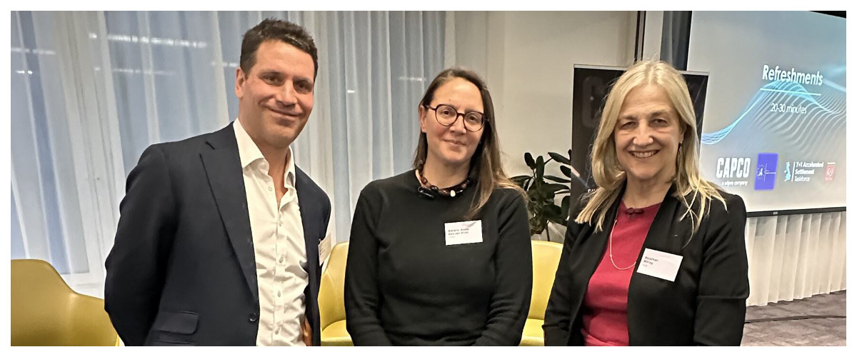 Three professionals networking at Capco event with presentation screen in background