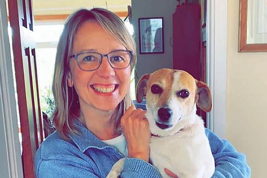 Image of Claudia smiling holding her dog in her arms.